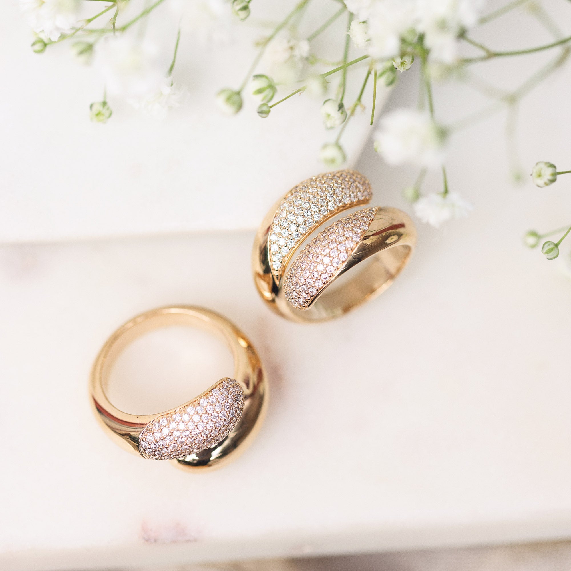 Bague dorée YOKO ZIRCONS - Bijou photographié sur marbre blanc avec petites fleurs blanches