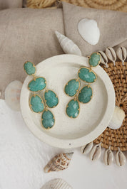Boucles d'oreilles pendantes dorées Leontine amazonite ornées de pierres naturelles - Bijou photographié dans un décor estival