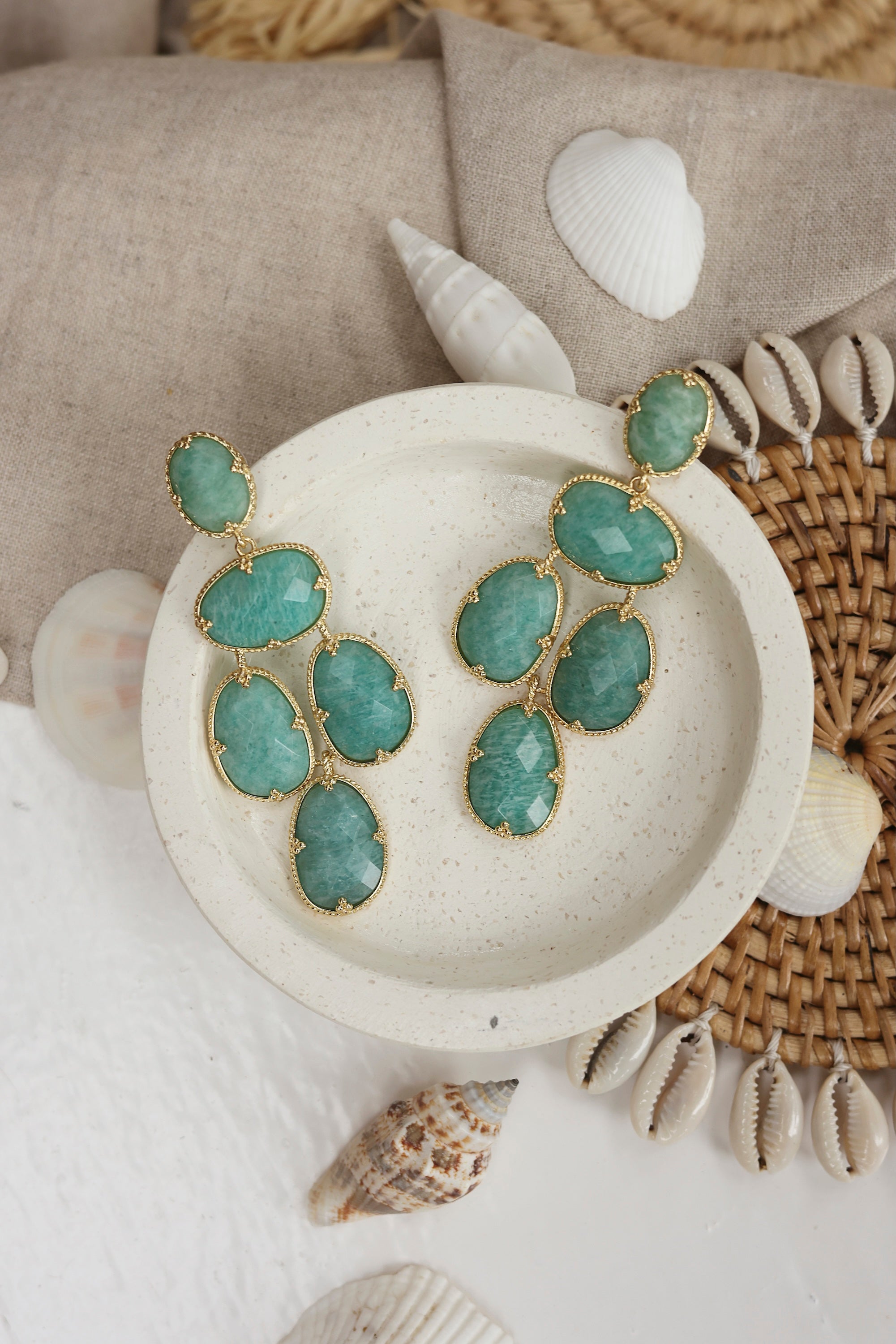 Boucles d'oreilles pendantes dorées Leontine amazonite ornées de pierres naturelles - Bijou photographié dans un décor estival