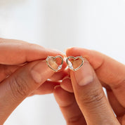 Boucles d’oreilles Galinda dorées cœurs zircons - Bijou photographié dans les mains 