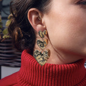 Boucles d’oreilles pendantes dorées composées de trois cœurs qui se suivent - Bijou porté