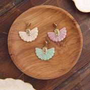 Boucles d’oreilles pendantes en acier inoxydable et acétate en forme d’éventail - Bijou photographié sur un plateau rond en bois