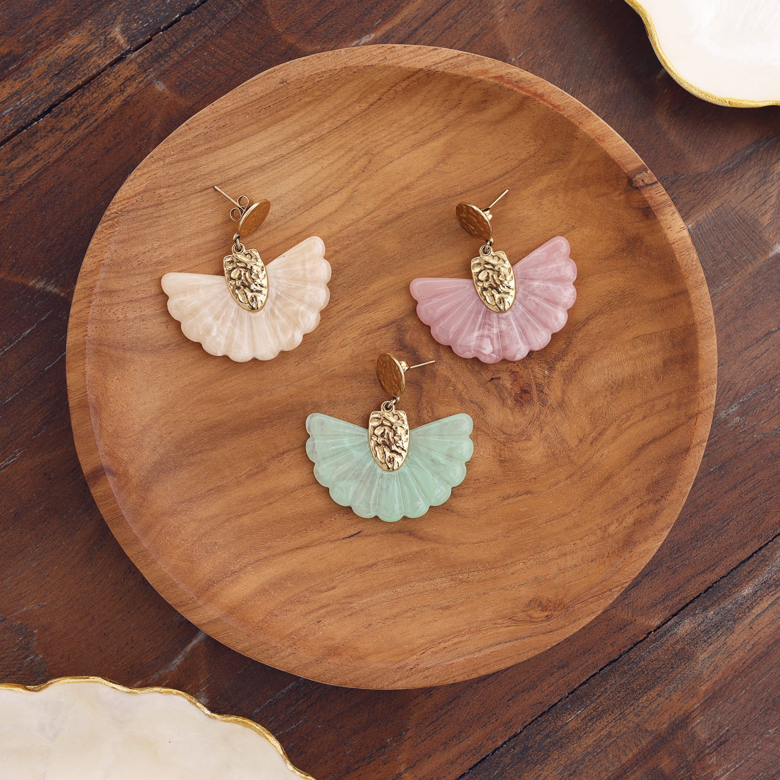 Boucles d’oreilles pendantes en acier inoxydable et acétate en forme d’éventail - Bijou photographié sur un plateau rond en bois