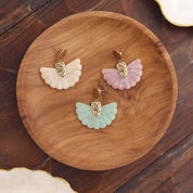 Boucles d’oreilles pendantes Luh écru en forme d’éventail - Bijou photographié dans un décor estival