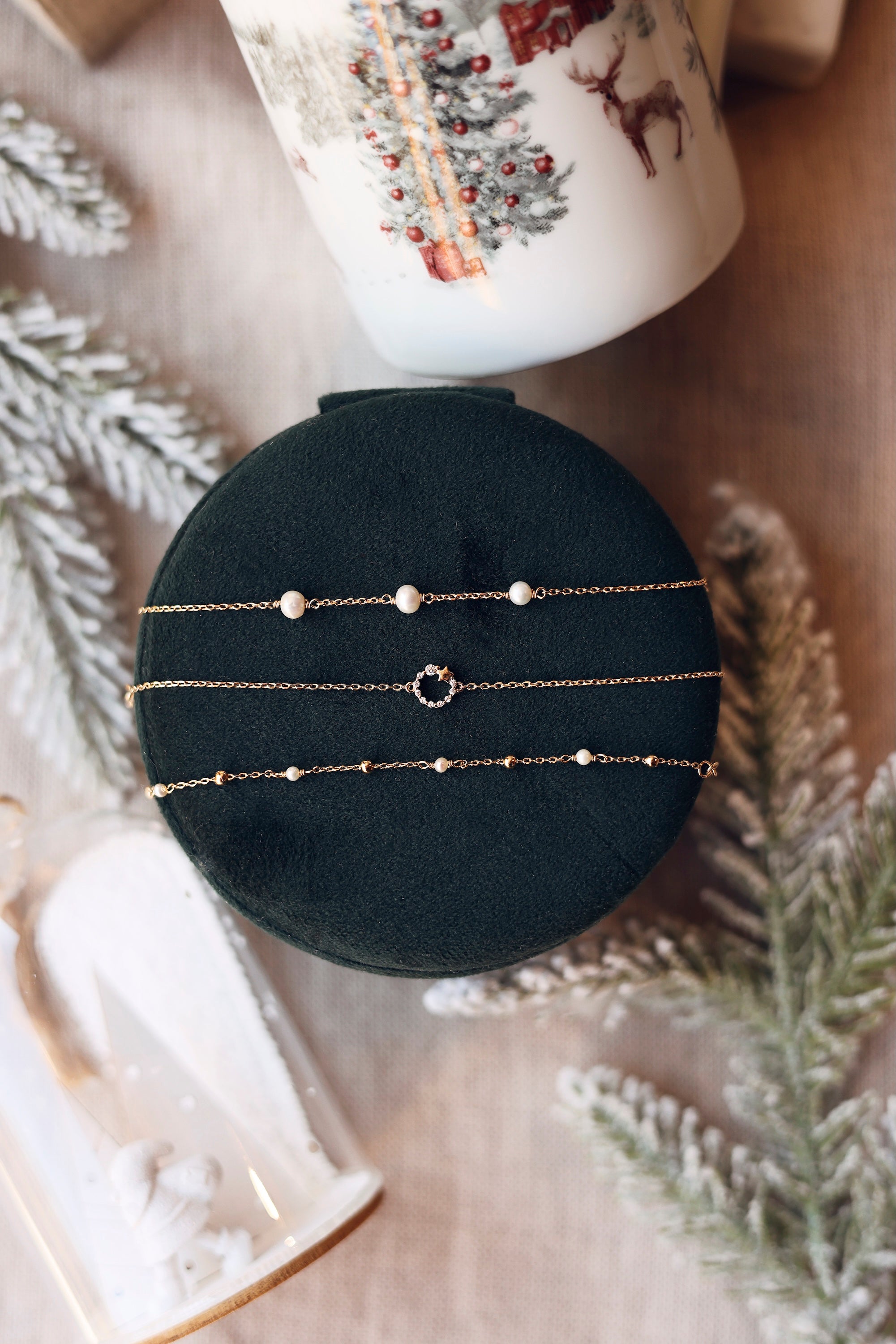 Bracelet doré Ariya orné de trois perles en nacre - Bijou photographié sur une boîte en velours vert