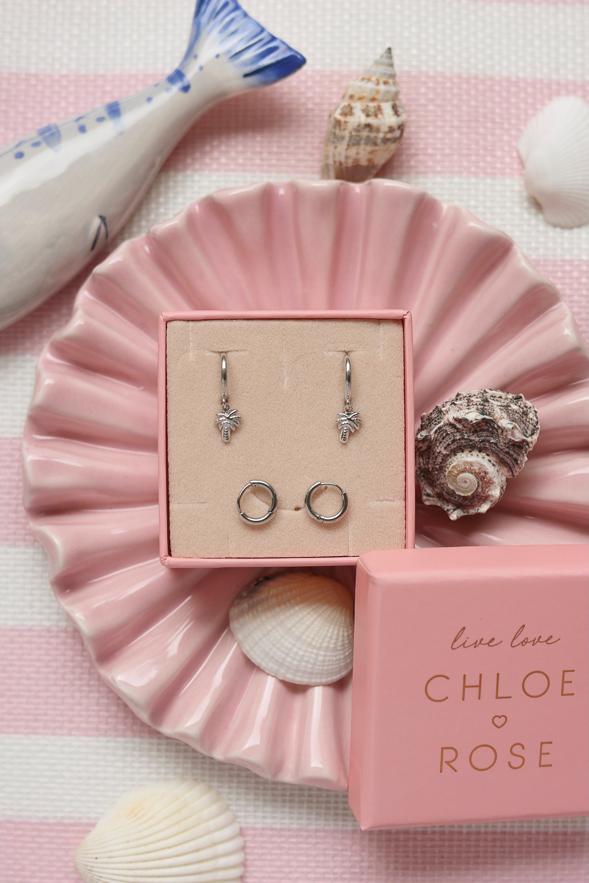 Coffret de parure de bijoux Palmier comprenant une paire de mini créoles argentées ornées d’un palmier ainsi qu’une paire de créoles simples - Bijoux photographiés dans un décor estival