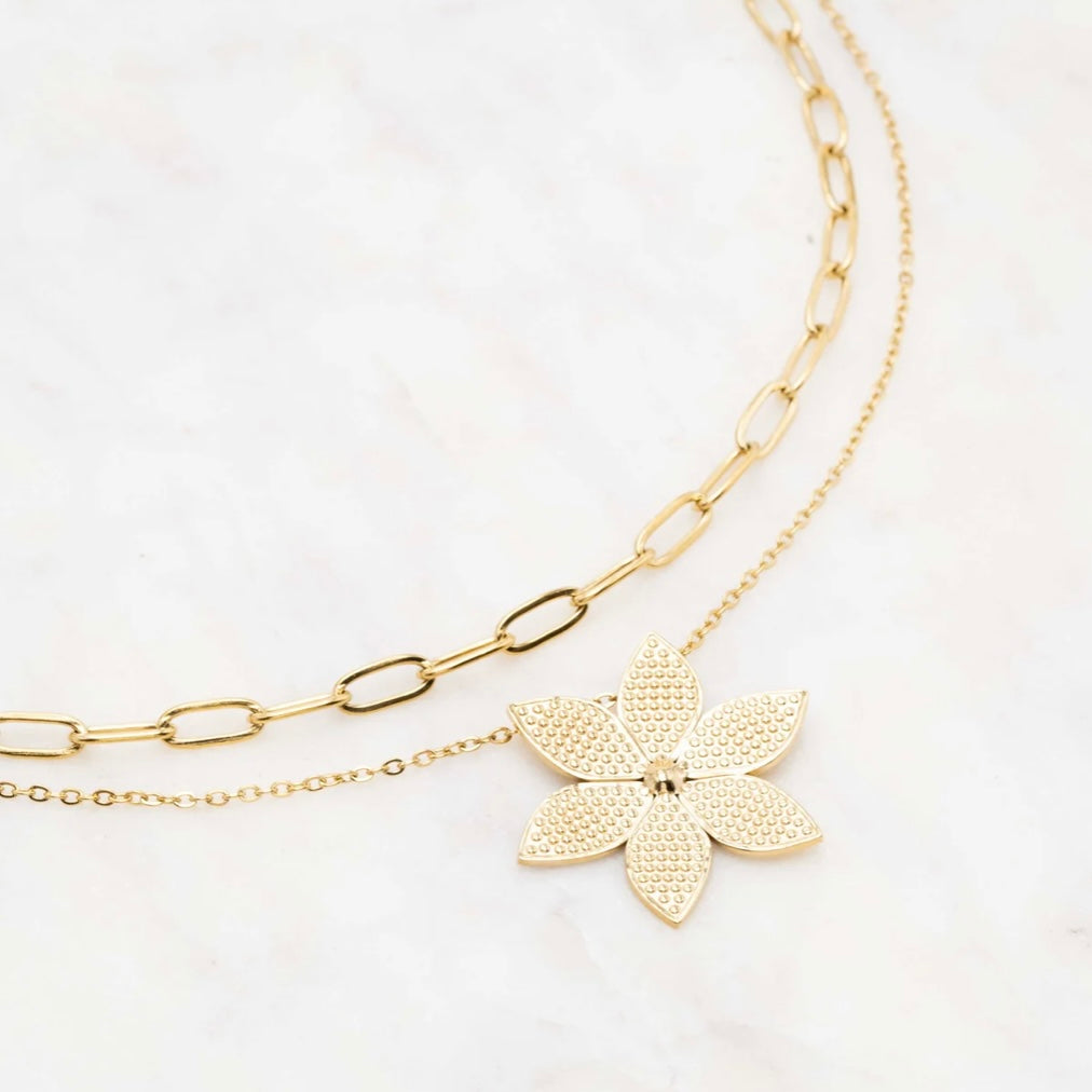 Collier Janan double en acier doré, composé d’une chaîne fine et d’une chaîne à mailles, avec un pendentif fleur - Bijou photographié sur fond blanc   