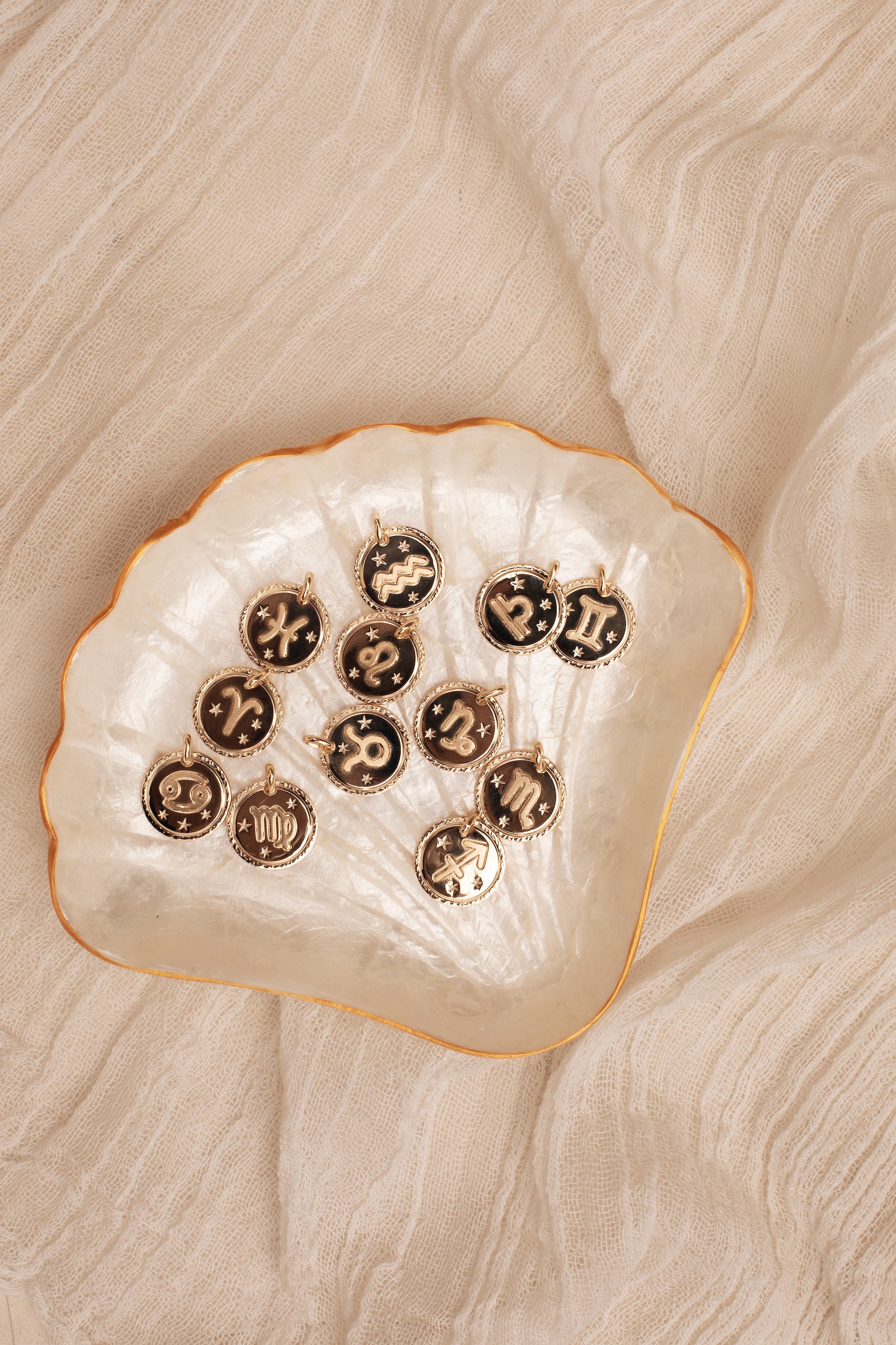 Collier doré signe du zodiaque Capricorne - Bijou photographié dans coupole en forme de coquillage en nacre