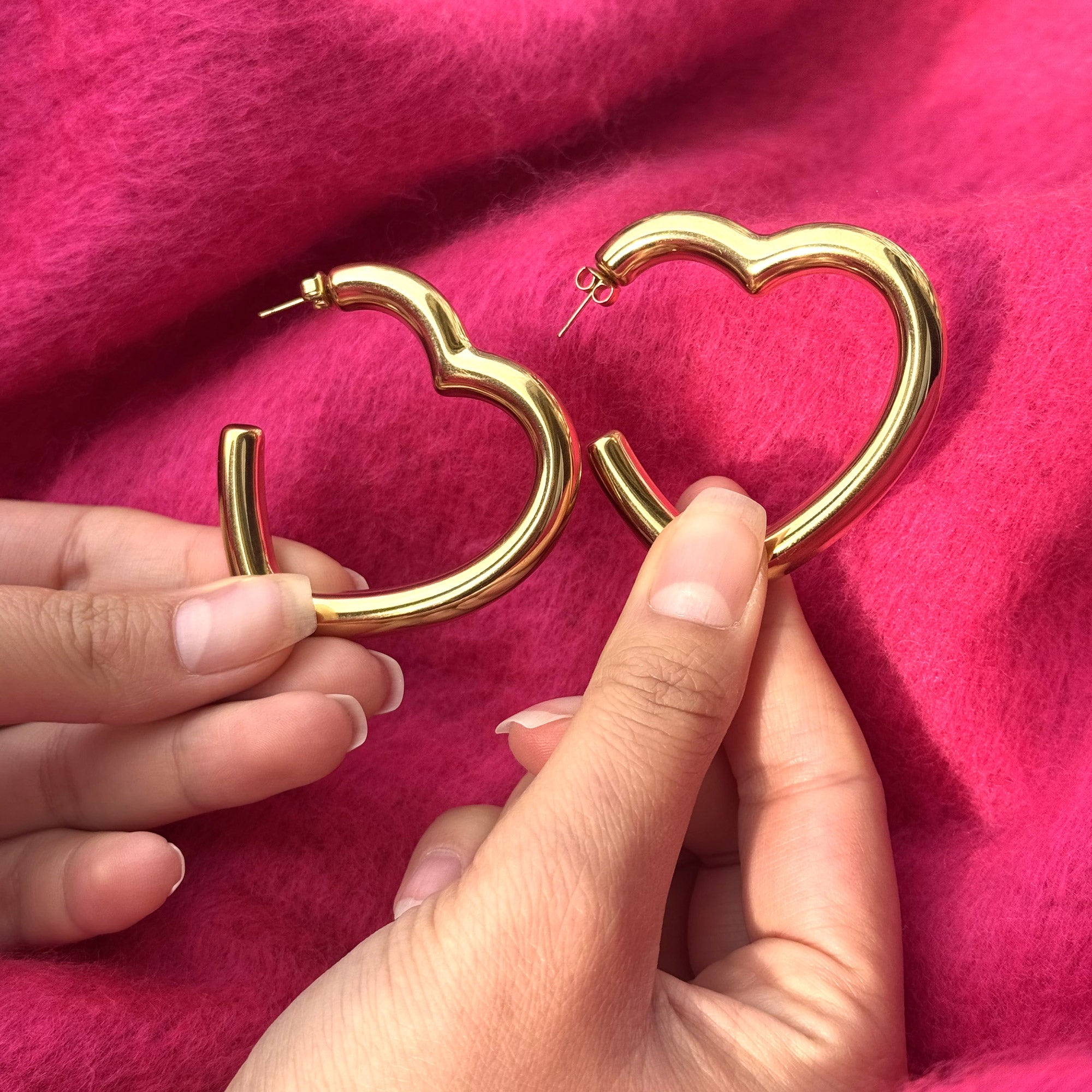 Créoles dorées Andrée en forme de cœur  - Bijou photographié sur un tissu rose 