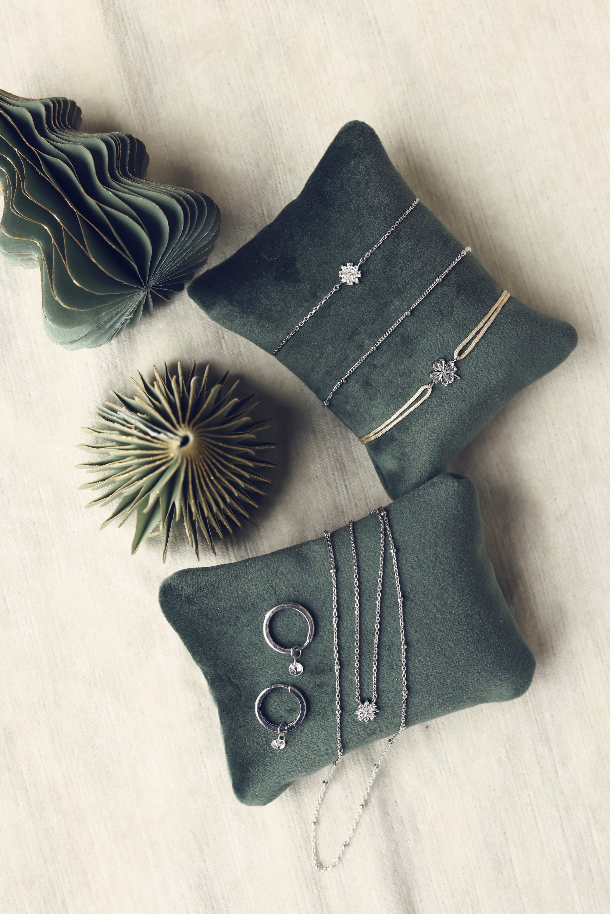 Le Fabuleux calendrier de l'Après version argent - Bijoux photographiés sur des coussins en velours verts entourés de petits sapins Chloé Rose 2025 