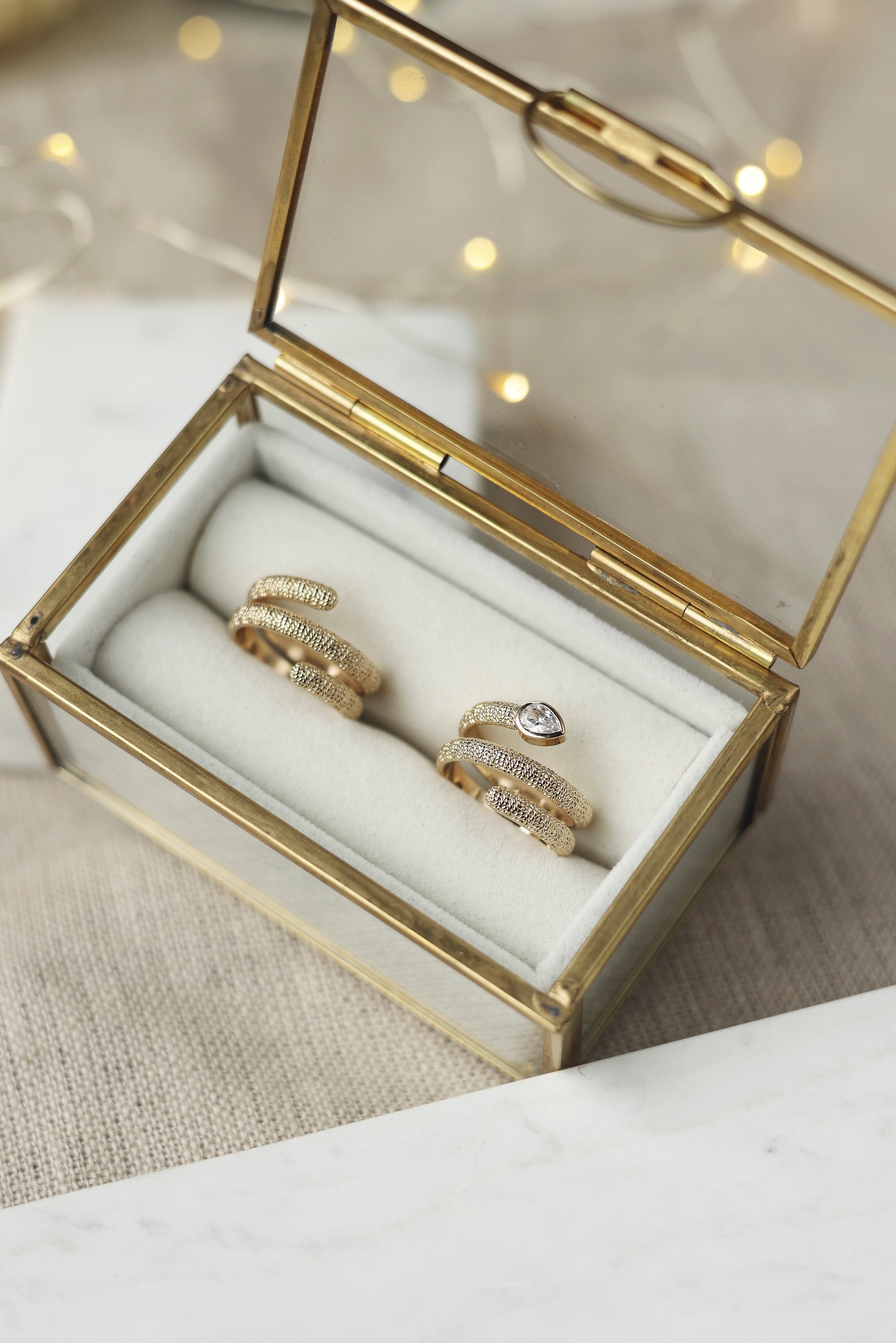 Bague dorée Abi zircon en spirale texturée ornée d'un zircon - Bijou photographié dans une boîte aux bordures dorées