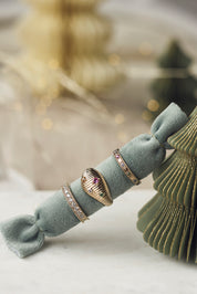 Bague dorée Marla de type anneau sertie de zircon - Bijou photographié sur un coussin bleu turquoise posé sur un sapin de Noël