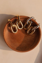 Boucles d'oreilles pendantes Camia dorées et argentées - Bijou photographié dans une coupole en bois