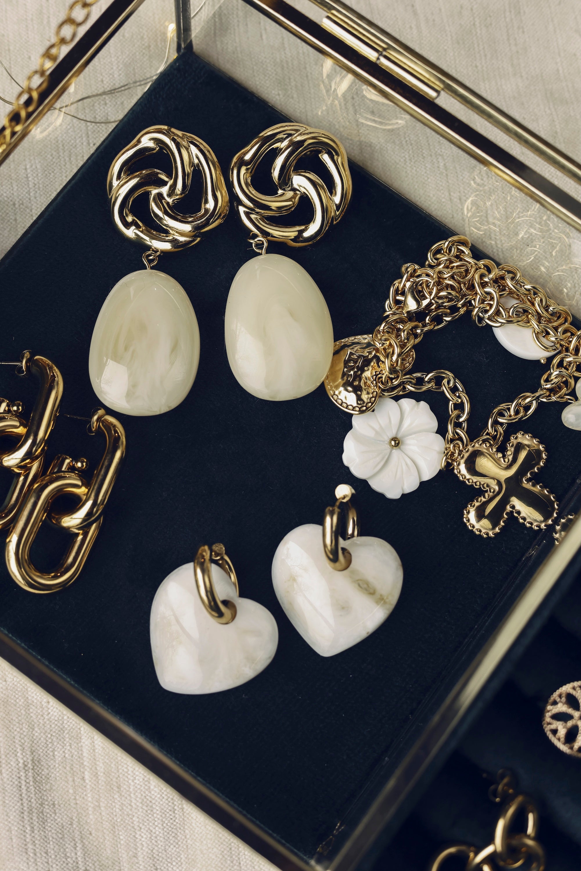 Boucles d'oreilles pendantes dorées Nali crème avec pendentif en acétate coloré - Bijou photographié dans une boîte à bijoux en velours vert