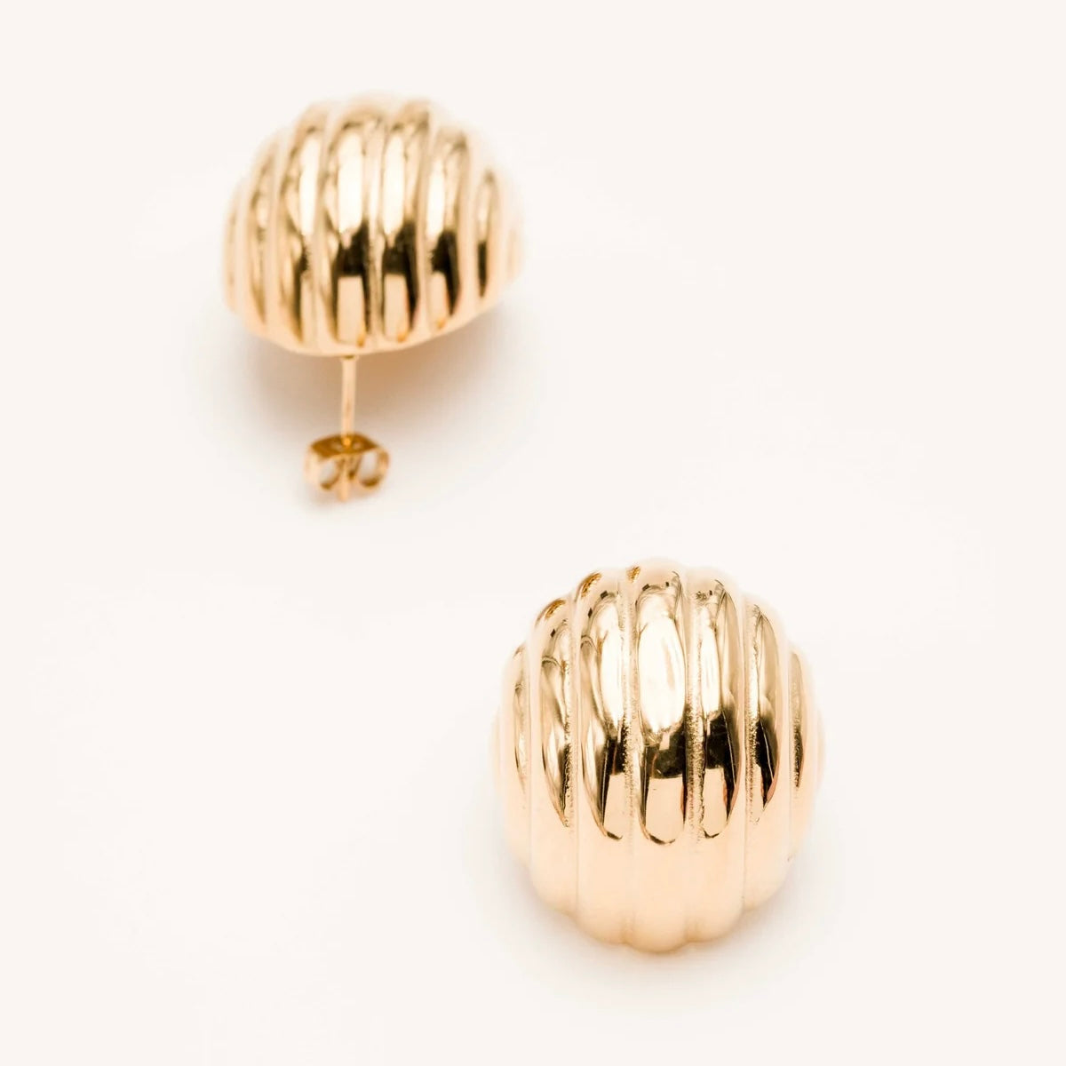 Boucles d'oreilles dorées Sonya - Bijou photographié sur fond beige