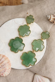 Boucles d'oreilles pendantes dorées Tharia aventurine motif trèfles ornées de pierres naturelles - Bijou photographié dans un décor estival