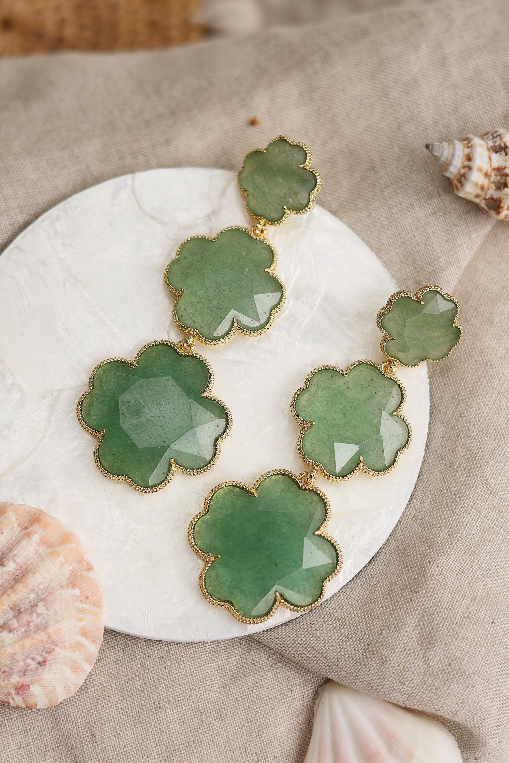 Boucles d'oreilles pendantes dorées Tharia aventurine motif trèfles ornées de pierres naturelles - Bijou photographié dans un décor estival