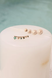 Boucles d'oreilles dorées Barrettes Enola fleurs - Bijou photographié sur présentoir en marbre blanc à côté d'une piscine