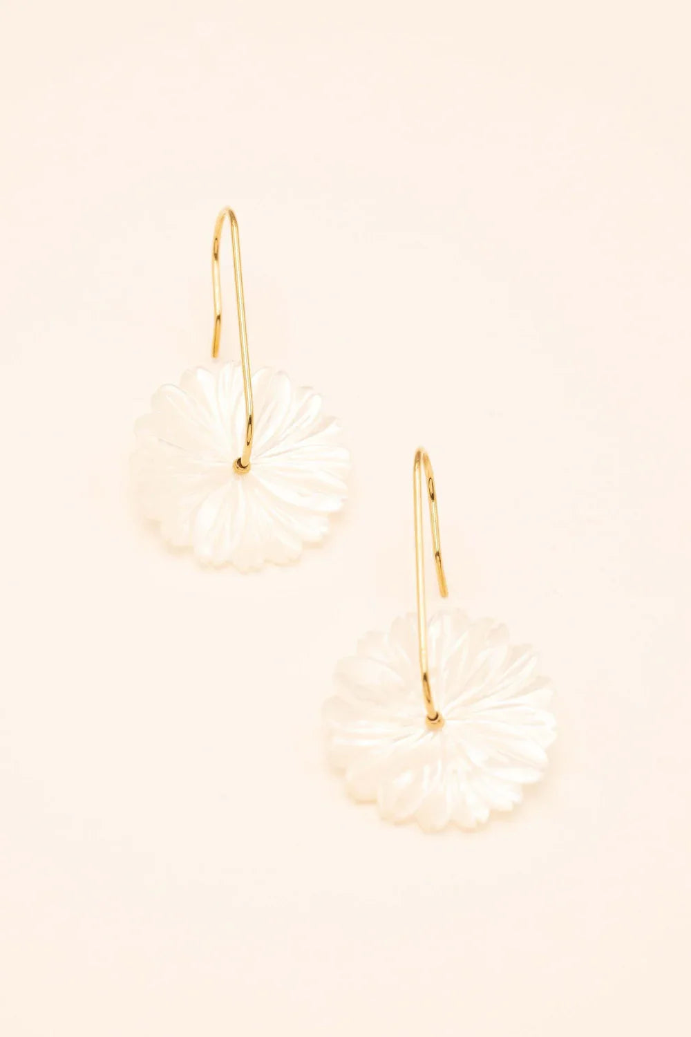 Boucles dorées Jasmina avec fleur en nacre - Bijou photographié sur fond beige