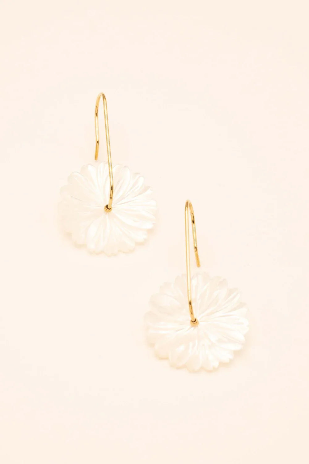 Boucles dorées Jasmina avec fleur en nacre - Bijou photographié sur fond beige