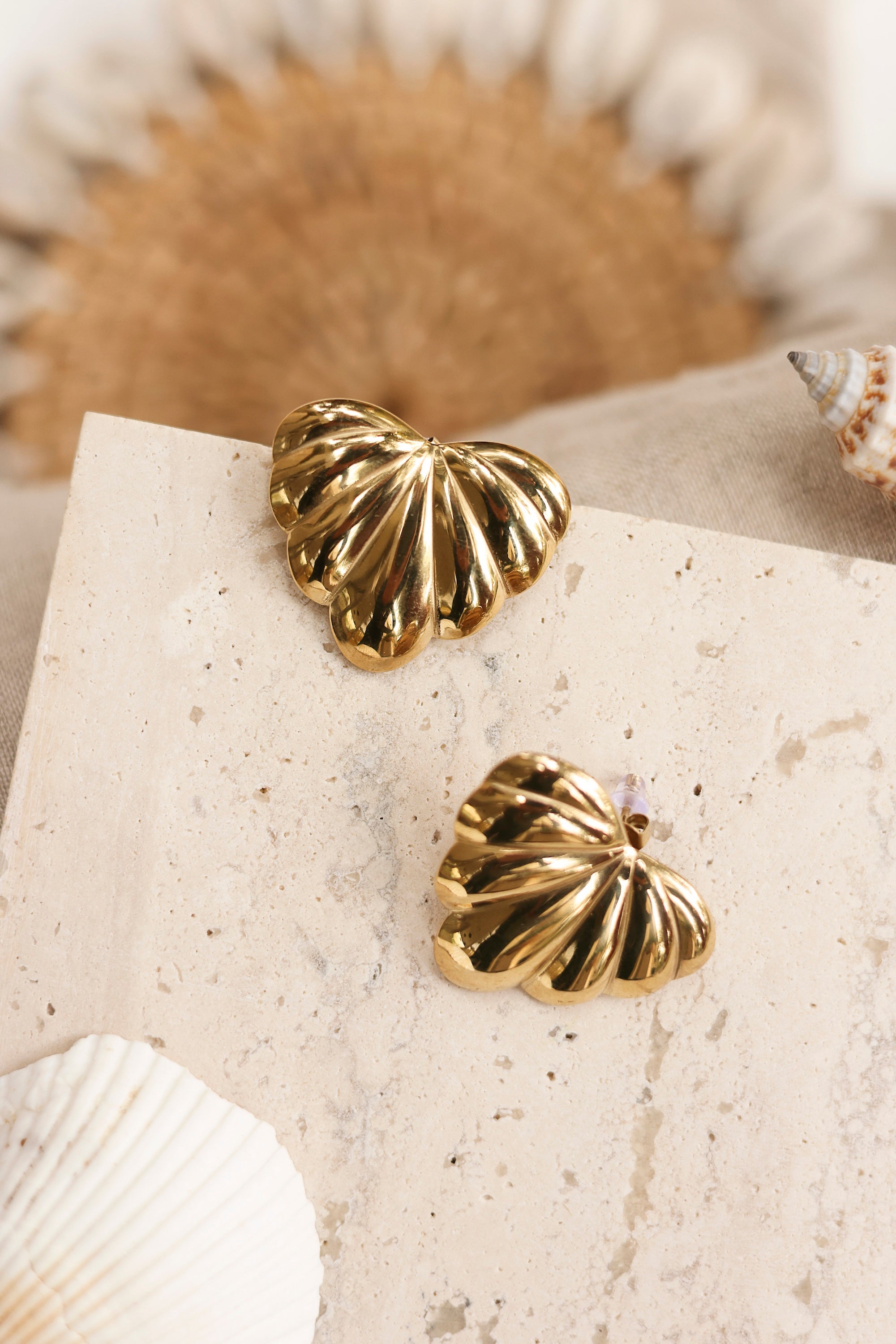 Boucles d'oreilles puces dorées Loulou en forme de feuille - Bijou photographié dans un décor estival