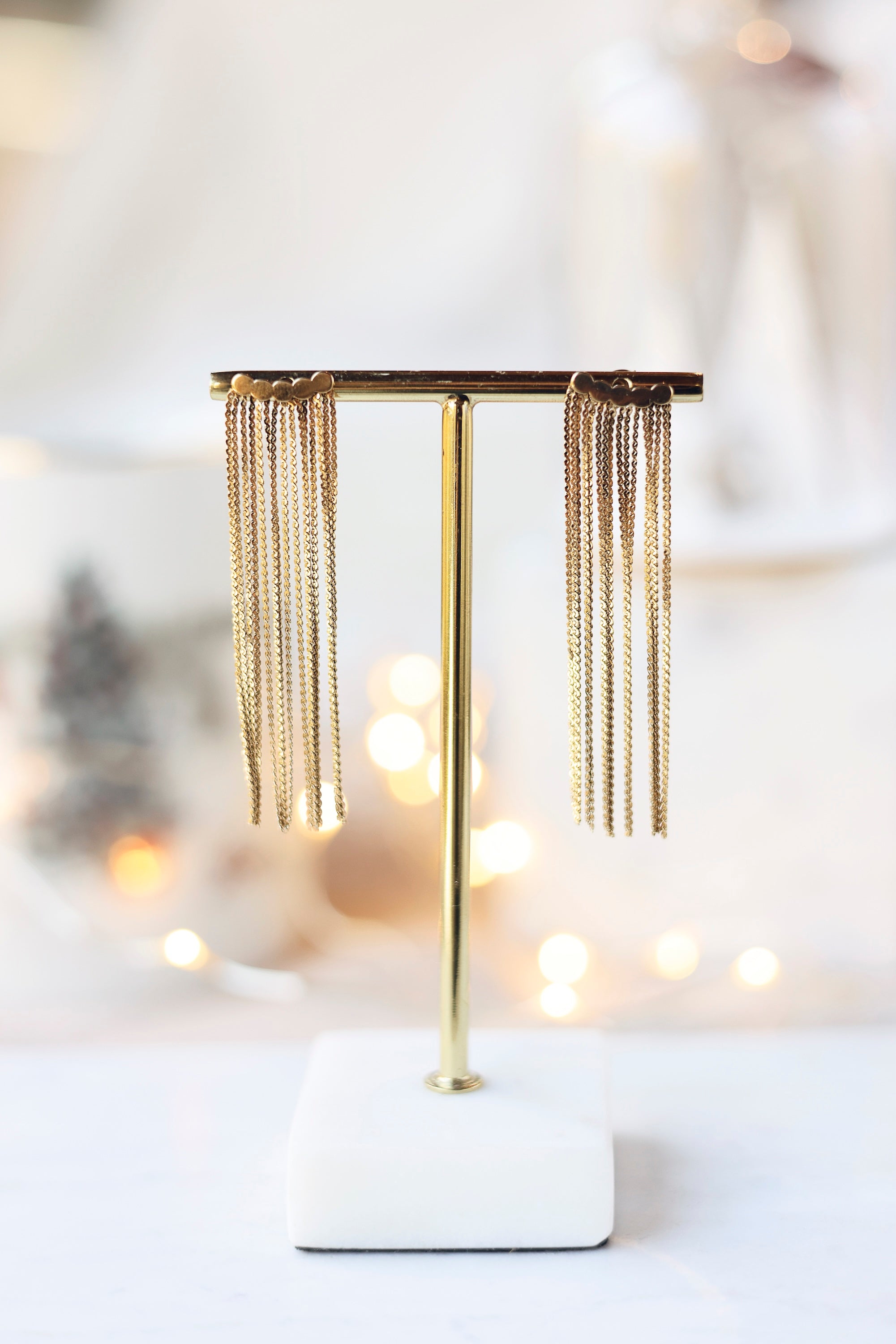 Boucles d'oreilles dorées Briana à chaînes pendantes - Bijou photographié sur un présentoir à boucles doré