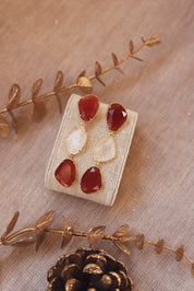 Boucles d'oreilles pendantes dorées Ninon ornées de pierres naturelles - Bijou photographié sur un présentoir en lin gris beige avec des décorations de Noël