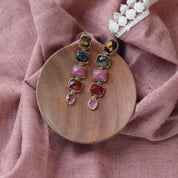 Boucles d'oreilles pendantes dorées pierres naturelles Shona - Bijou photographié dans une coupole en bois sur un tissu rose