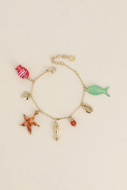 Bracelet doré Connie chaîne torsadée avec pendentifs coquillage, étoile de mer, poissons, cœur et pierres naturelle - Bijou photographié sur fond beige
