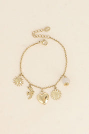 Bracelet doré Lorena chaîne fine avec pendentifs soleil, hirondelle, coeur, tournesol et pierre naturelle - Bijou photographié sur fond beige
