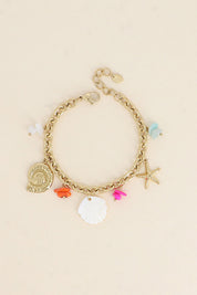 Bracelet maille doré Larysa pendentifs coquillage en nacre, coquillage doré, étoile de mer et pierres colorées - Bijou photographié sur fond beige