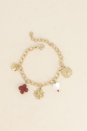 Bracelet maille doré Sabeen pendentifs soleil, cœur, trèfle et nacre - Bijou photographié sur fond beige