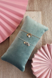 Bracelet personnalisable en argent Ama pendentifs étoiles pour lettre ou charm - Bijou photographié sur un coussin turquoise