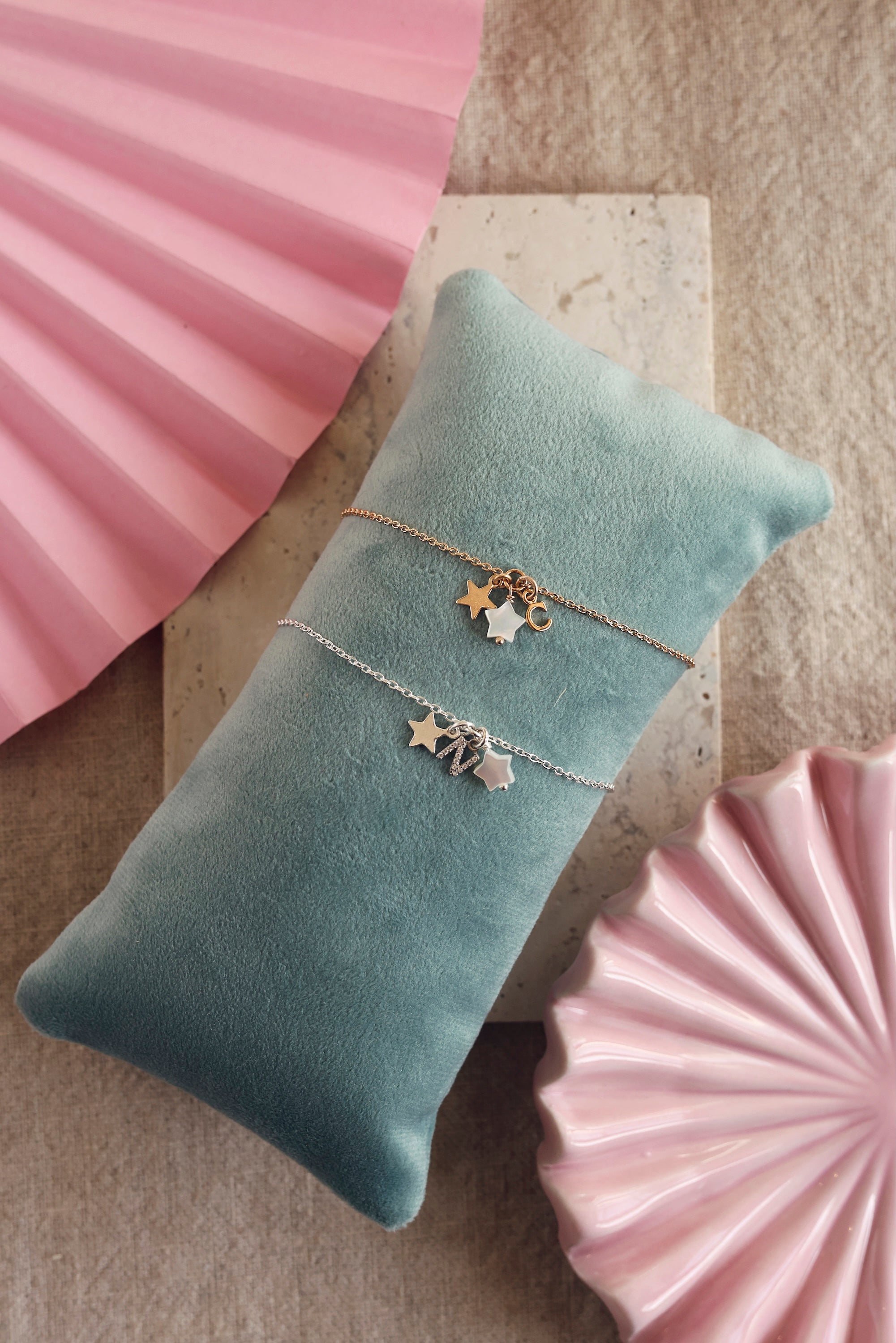 Bracelet personnalisable en argent Ama pendentifs étoiles pour lettre ou charm - Bijou photographié sur un coussin turquoise