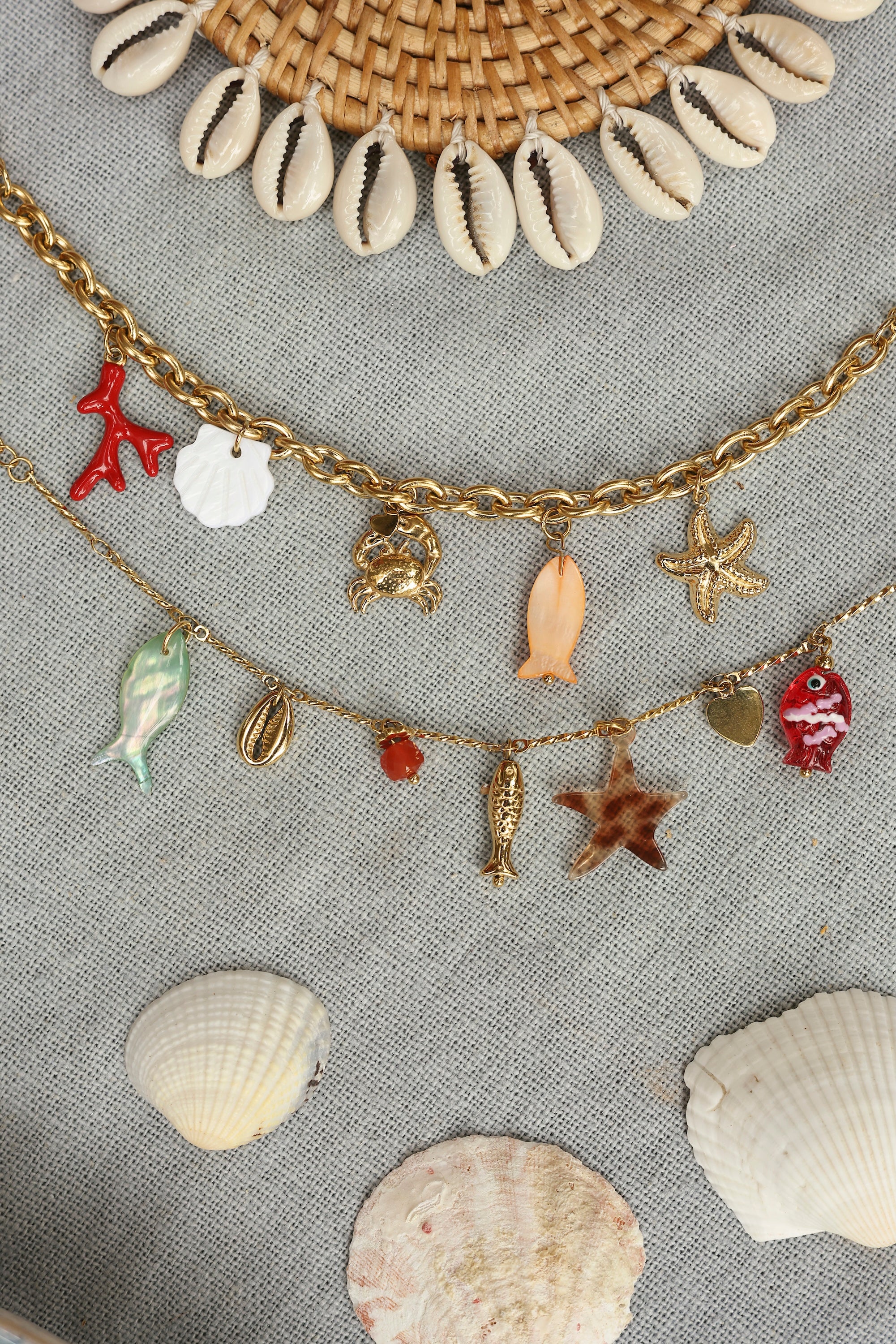 Bracelet doré Connie chaîne torsadée avec pendentifs coquillage, étoile de mer, poissons, cœur et pierres naturelle - Bijou photographié dans un décor estival