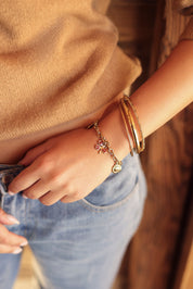 Bracelet en maille doré Elias avec pendentifs soleil, trèfle, cœur et hirondelle - Bijou porté