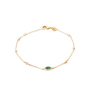 Bracelet doré Alvina à chaîne fine orné de zircons blancs et d’un zircon vert en forme d’œil - Bijou sur fond blanc