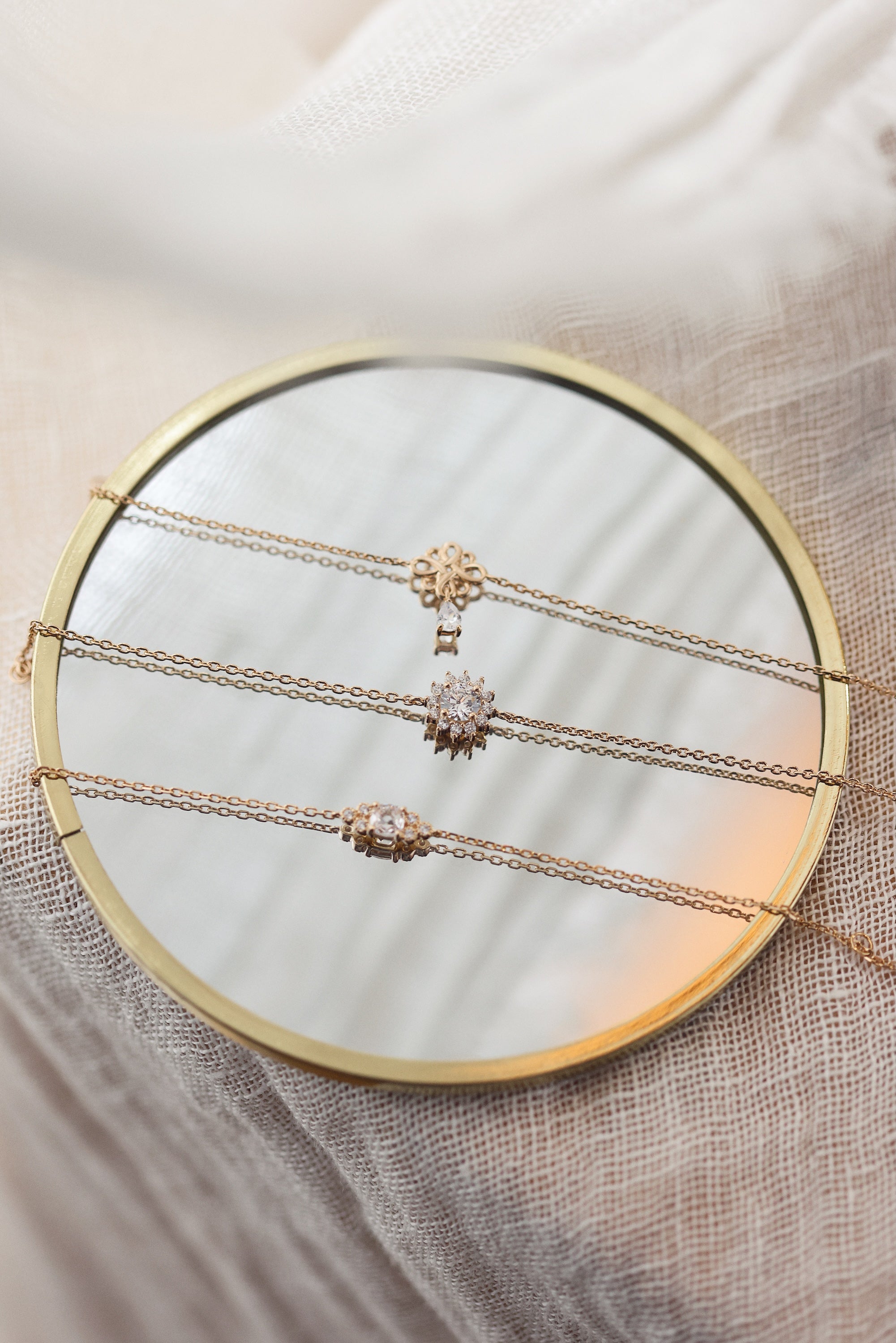 Bracelet doré, zircon blanc central entouré de zircons blancs - Bijou photographié sur un miroir