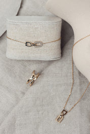 Bracelet doré Berny motif étrier serti de zircons - Bijou photographié sur présentoir en lin gris