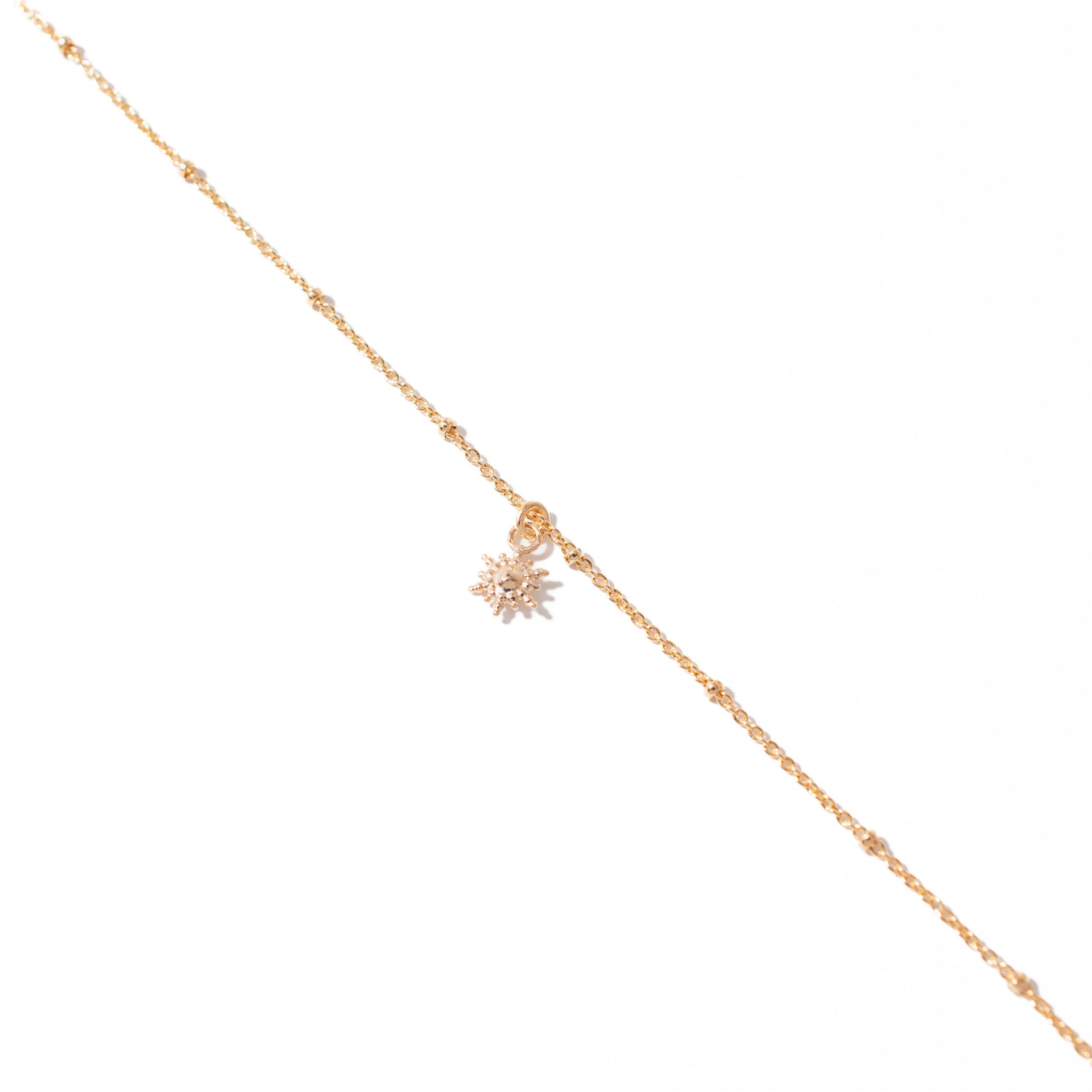 Chaîne de cheville dorée Priya avec pendentif soleil - Bijou photographié sur fond blanc