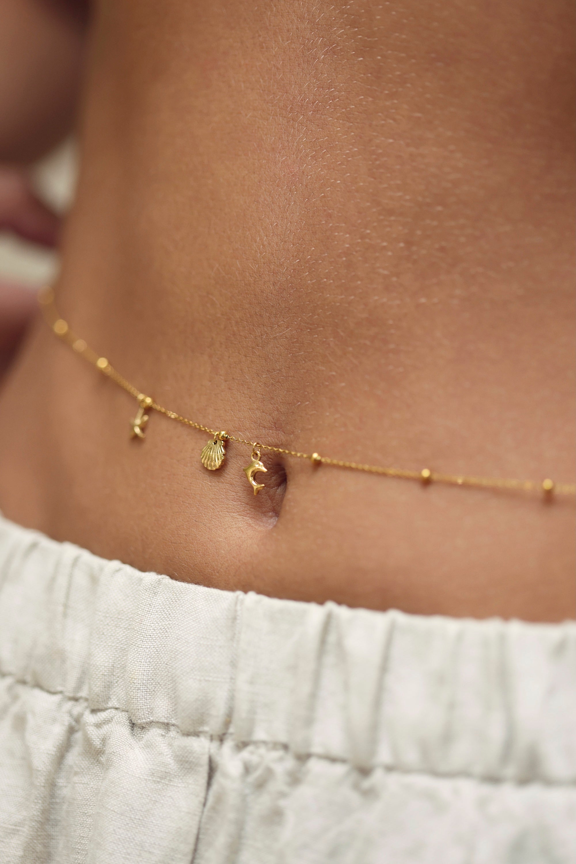 Chaîne de taille dorée Alezia perlée avec pendentifs dauphin, étoile de mer et coquillage - Bijou porté