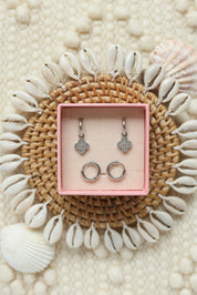 Coffret de parure de bijoux Shore comprenant une paire de mini créoles argentées ornées d’une fleur sertie de zircons ainsi qu’une paire de créoles simples - Bijoux photographiés dans un décor estival