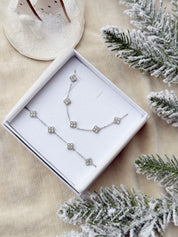 Coffret de parure Dolce comprenant un collier et un bracelet argentés, ornés de petites fleurs serties de zircons - Bijoux photographiés dans un écrin à bijoux blanc dans une ambiance de Noël
