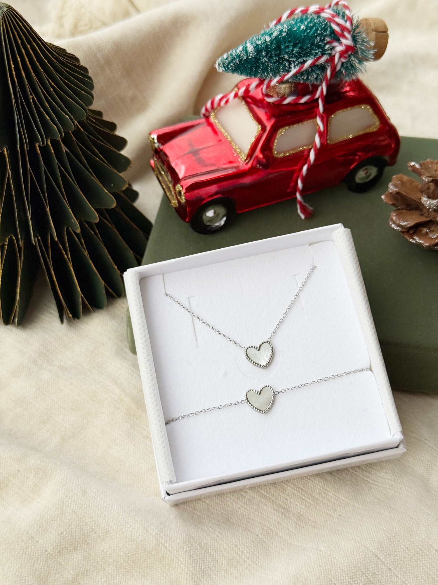 Coffret de parure Heart comprenant un collier et un bracelet argentés, ornés de coeurs en nacre - Bijoux photographiés dans un écrin à bijoux blanc dans une ambiance de Noël