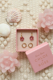 Coffret de parure de bijoux Sunday fuchsia comprenant une paire de mini créoles dorées ornées d'un anneau en perles dorées et fuchsia ainsi qu’une paire de créoles simples - Bijoux photographiés dans un décor estival