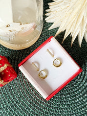 Coffret de parure de bijoux Divine contenant deux paires de mini créoles dorées ornées de zircons - Bijoux photographiés dans un écrin à bijoux rouge dans une ambiance de Noël