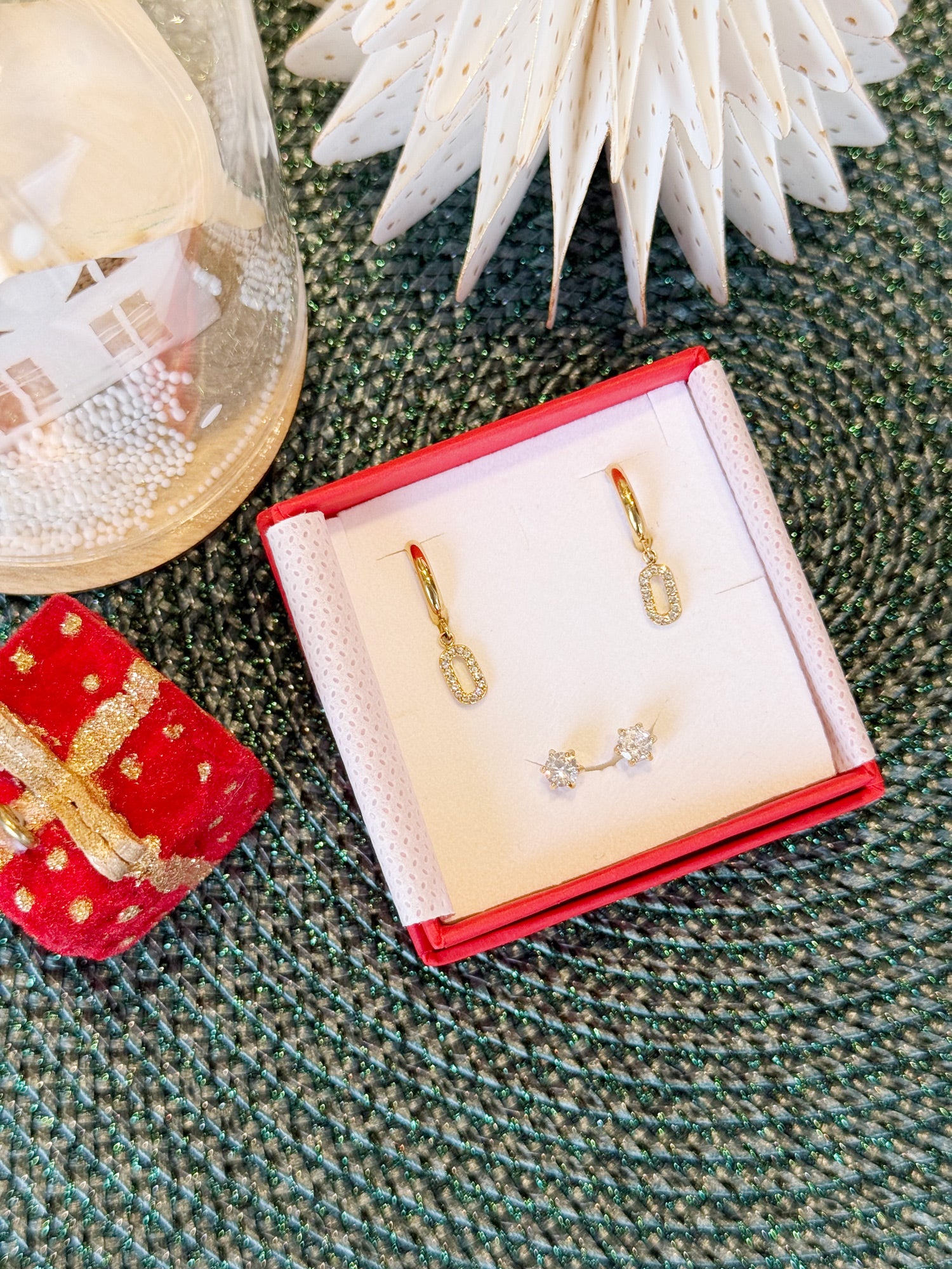 Coffret de parure de bijoux Blush contenant une paire de mini créoles avec des pendentifs rectangles ovalisés et une paire de puces dorées - Bijoux photographiés dans un écrin à bijoux rouge dans une ambiance de Noël
