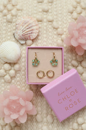 Coffret de parure de bijoux Sunday vert turquoise comprenant une paire de mini créoles dorées ornées d'un anneau en perles dorées et vert ainsi qu’une paire de créoles simples - Bijoux photographiés dans un décor estival