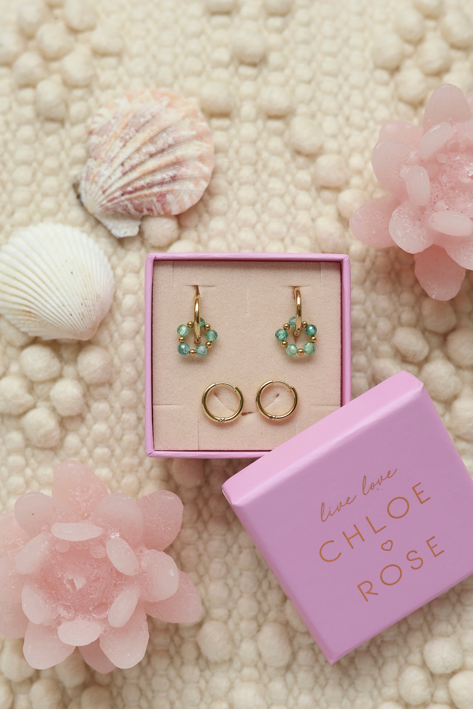Coffret de parure de bijoux Sunday vert turquoise comprenant une paire de mini créoles dorées ornées d'un anneau en perles dorées et vert ainsi qu’une paire de créoles simples - Bijoux photographiés dans un décor estival