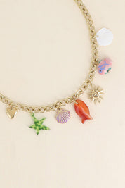 Collier maille doré Melania avec pendentifs coquillages, poissons, étoile de mer, soleil et coeur - Bijou photographié sur fond beige